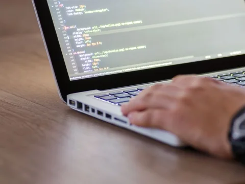 Hands typing code on a laptop